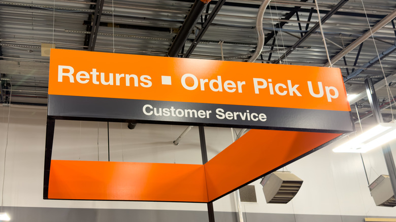 An orange sign for customer service at a grocery store, with returns and order pick up written in a big font.