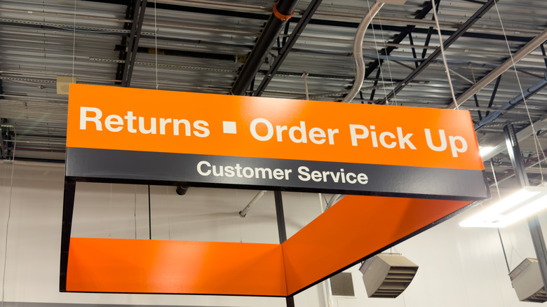 An orange sign for customer service at a grocery store, with returns and order pick up written in a big font.