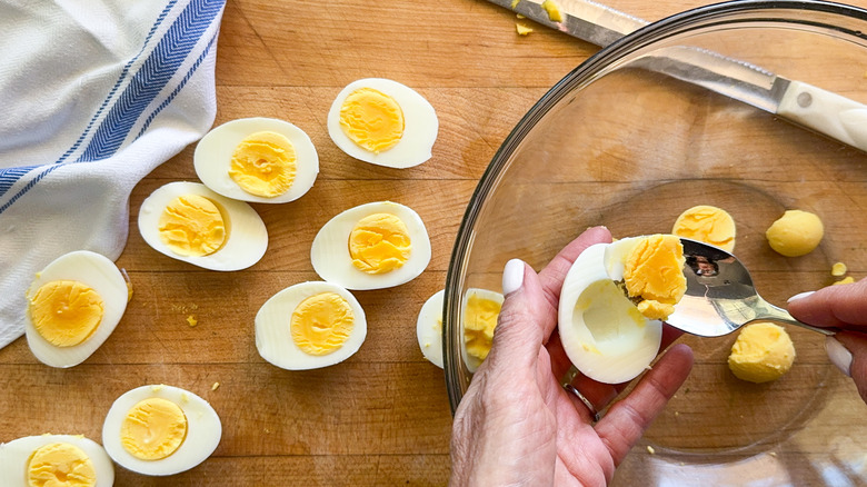 hand scooping egg yolk into bowl