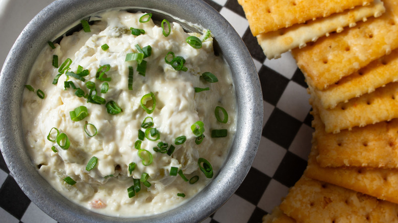 Bowl of pimiento cheese dip with chives and saltines