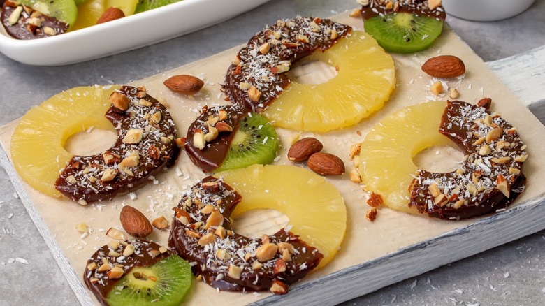 Rings of chocolate covered pineapple with chopped nuts