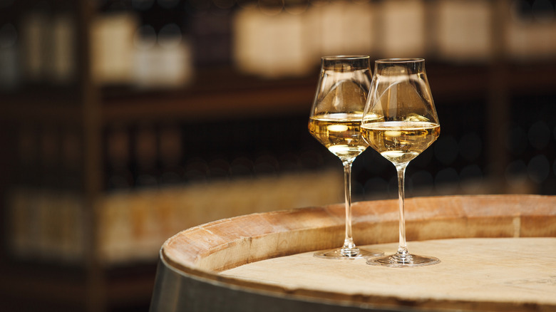 Two glasses of white wine on an oak barrel.