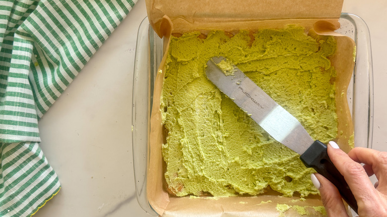 hand spreading cream over ladyfingers