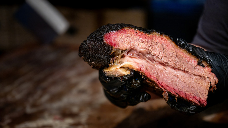 A chef holding a piece of brisket.