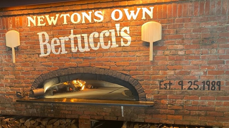 A brick oven in brick wall that reads "Newton's Own Bertucci's, Est. 9.25.1989".