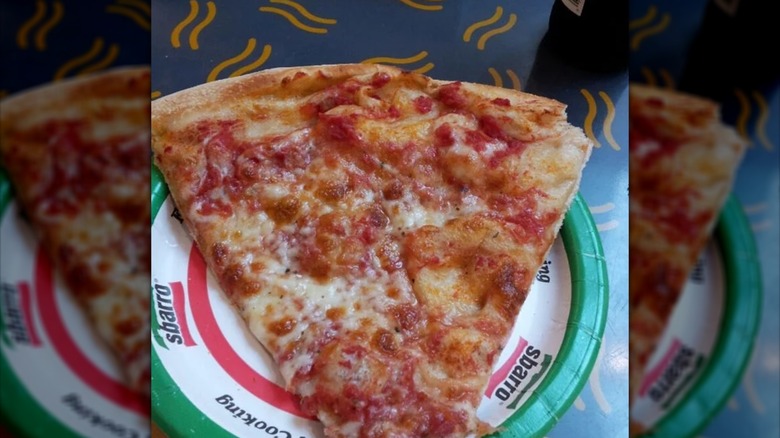 A large slice of pizza on a red, white, and green Sbarro plate.