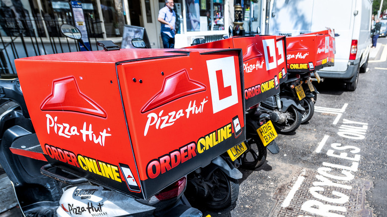 Pizza Hut delivery scooters lined up on a street
