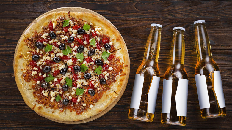Pizza with three bottles of beer on a wooden table