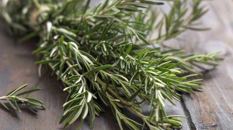 Rosemary is photographed in closeup on a wooden table.