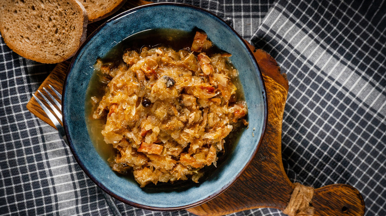 A bowl of bigos stew on a blue tablecloth.