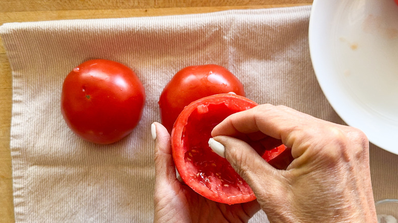 hand adding salt to tomato
