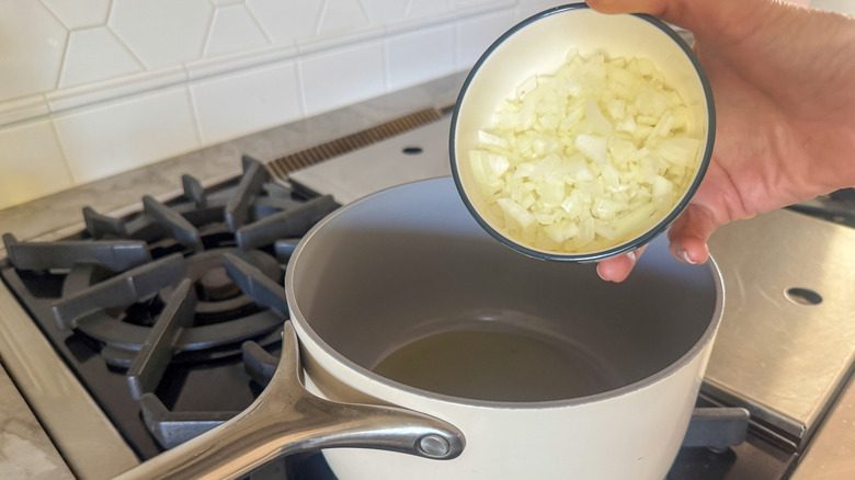 hand adding onion to pan