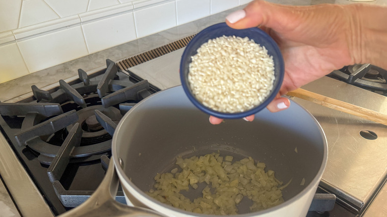 hand adding rice to pot