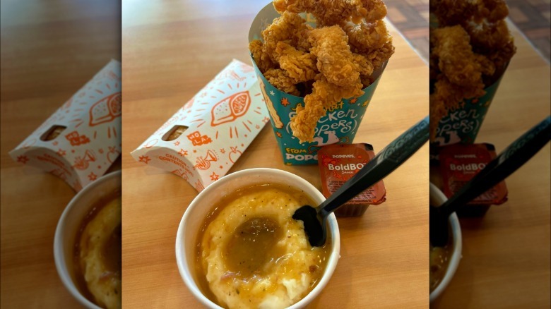 Popeyes' chicken dippers, mashed potatoes, BBQ sauce, and a pie on a wooden table