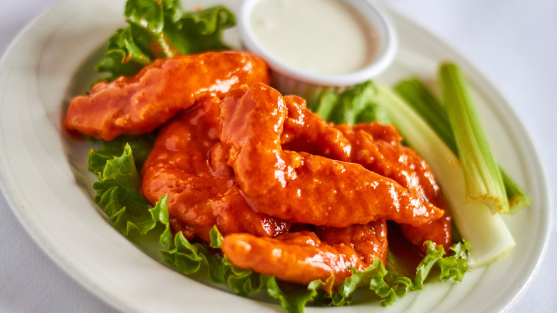 Buffalo chicken tenders on a bed of lettuce with celery and ranch dressing