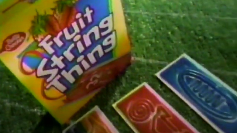 A grainy image of a colorful box of Fruit String Thing, with designs laid out in front