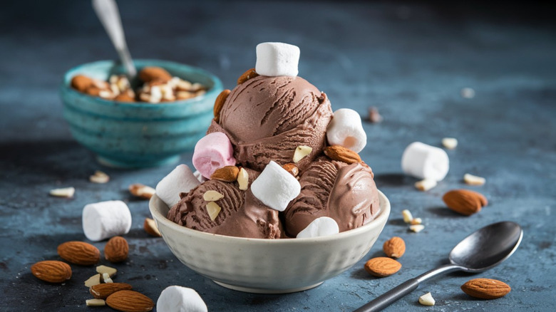 A bowl filled with Rocky Road ice cream, topped with nuts and marshmallows