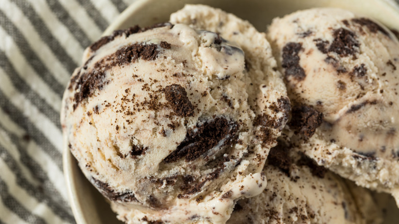 A bowl of cookies and cream ice cream against a striped tablecloth