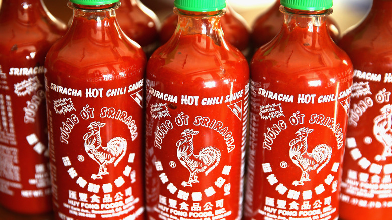 A closeup shot of three bottle of sriracha hot chili sauce