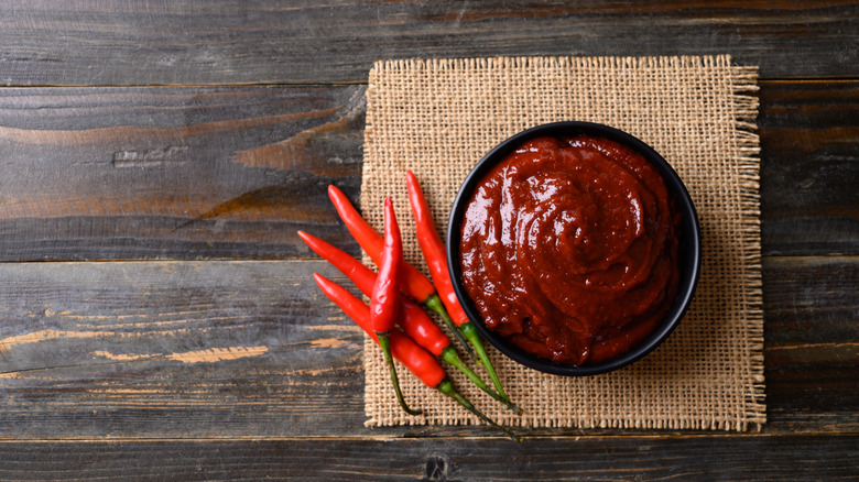 Bowl of gochujang with red chilies on the side