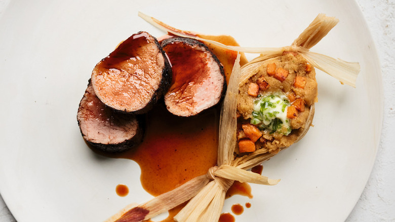 Pork tenderloin sliced on a wooden cutting board.