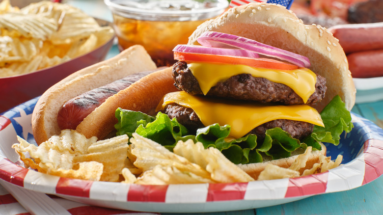 a hot dog and burger on a plate with chips