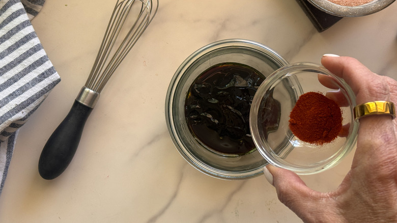 hand adding spices to marinade