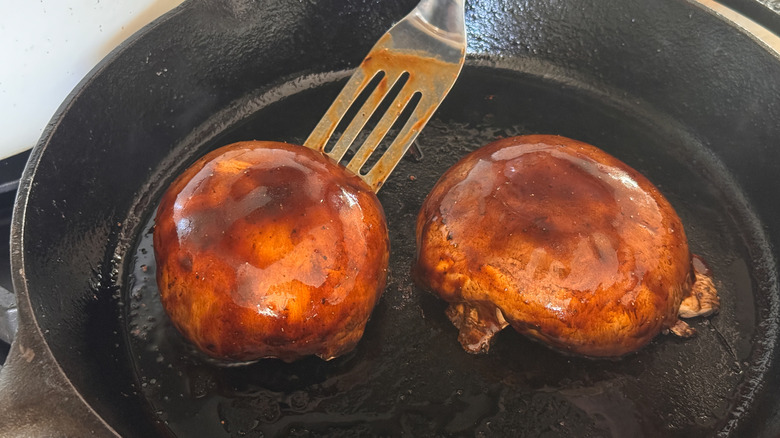 hand flipping mushrooms in skillet
