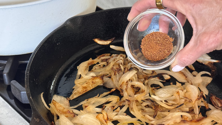 hand adding brown sugar to pan