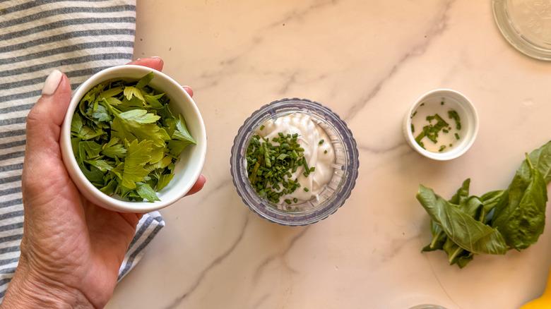 hand adding parsley to small blender