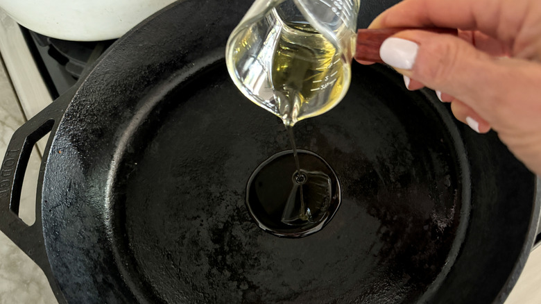 hand adding oil to pan