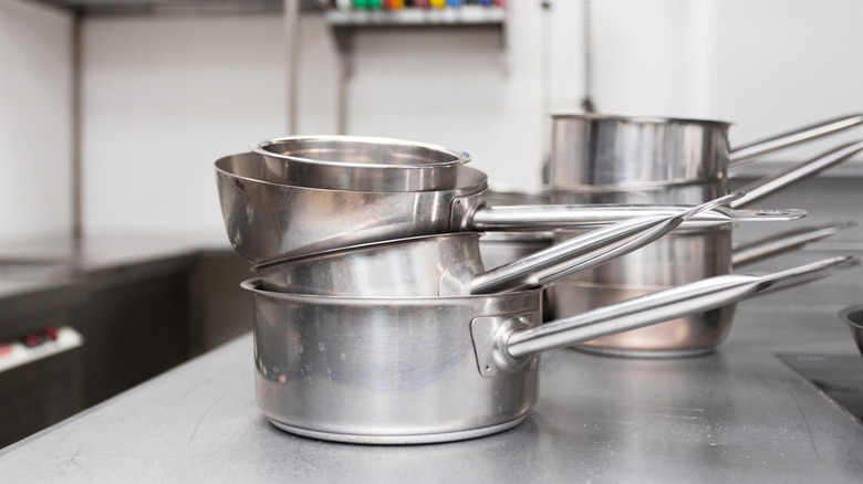 Stainless steel pots stacked in a kitchen.