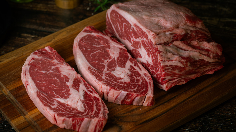 Ribeye is sliced on a wooden cutting board.