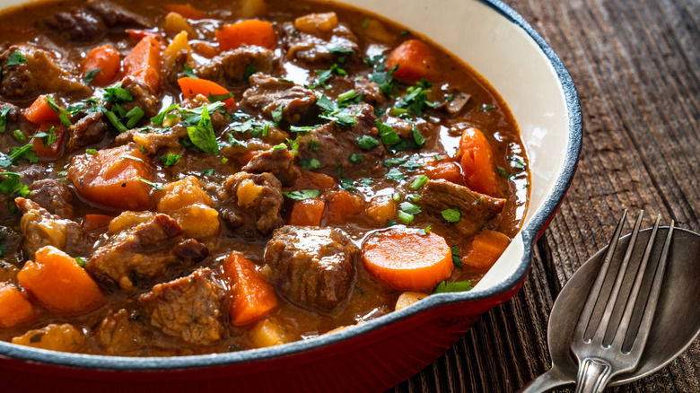 A large pot of pot roast features meat, carrots, and other vegetables.