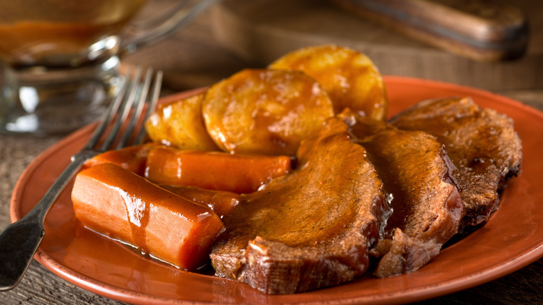 Sliced pot roast, carrots, and potatoes covered with gravy