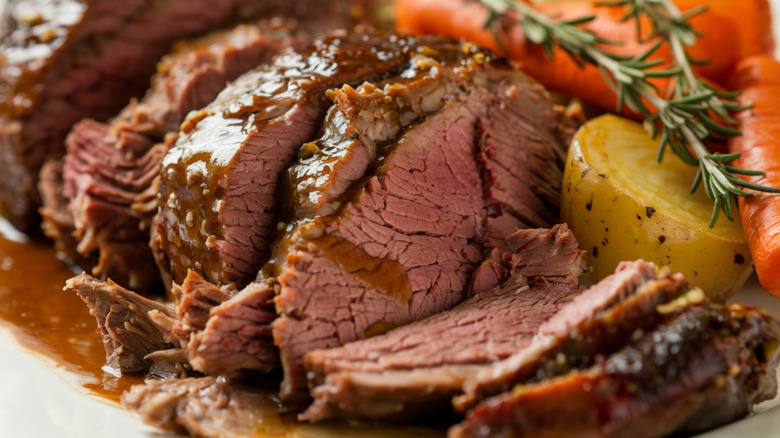 A slow-cooked beef roast is cooked with carrots, potatoes, and onions, simmered until tender and flavorful, perfect for a hearty family dinner.