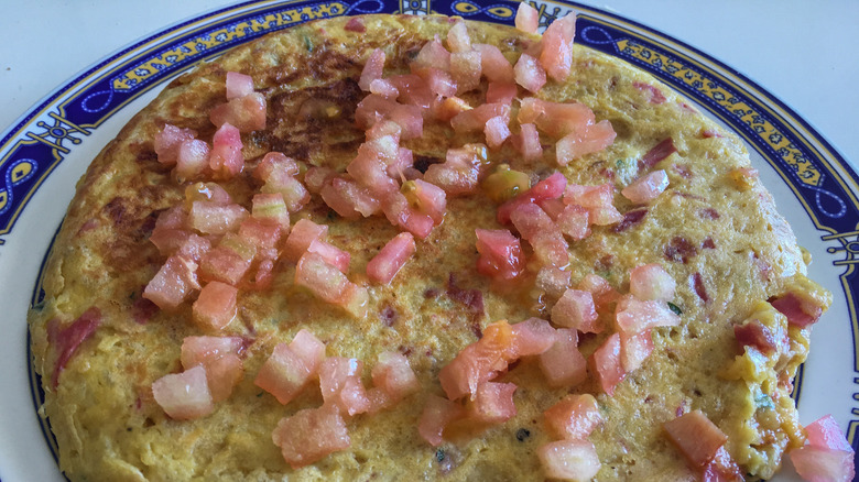 A Spanish omlet with chips topped with tomatoes