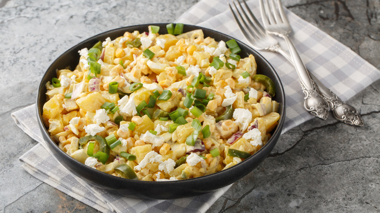 A bowl of Mexican corn potato salad garnished with chopped green onions