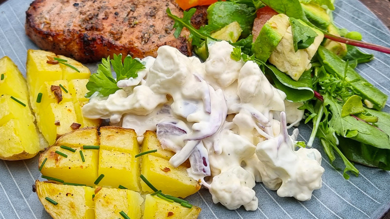 A plate filled with different dishes, including Norwegian potato salad, vegetables, boiled potatoes, and meat