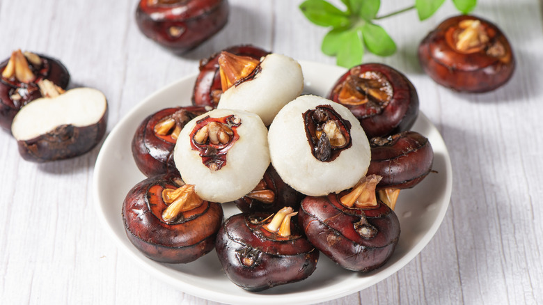 peeled and unpeeled water chestnuts in a white bowl