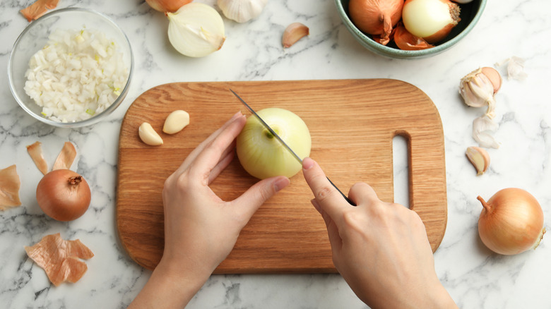 Hands cutting an onion.