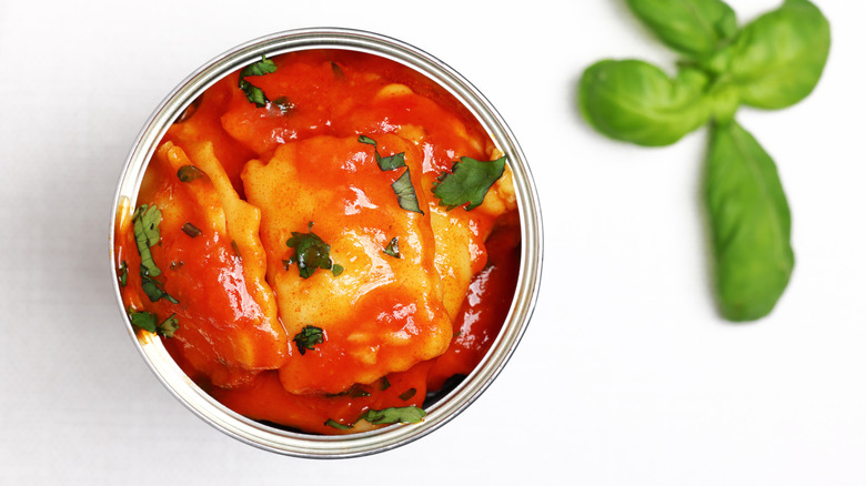 An above-shot of canned ravioli sprinkled with pieces of fresh herbs