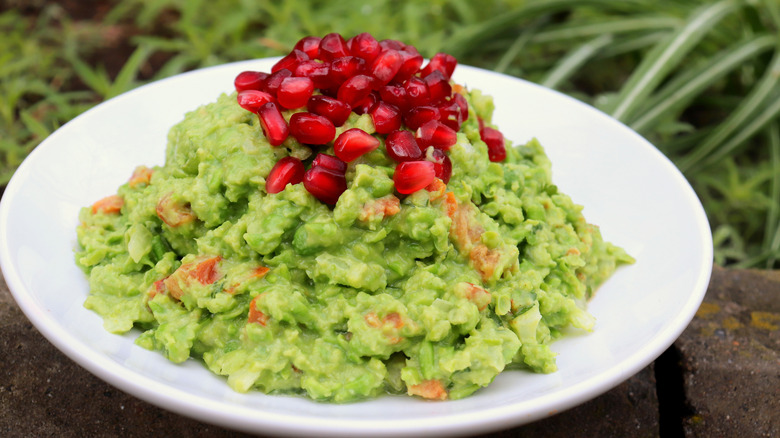 Bowl of pea guacamole topped with pomegranate seeds
