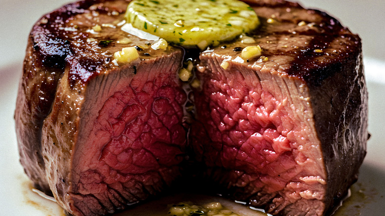 A seared filet mignon sliced in half and topped with melted butter
