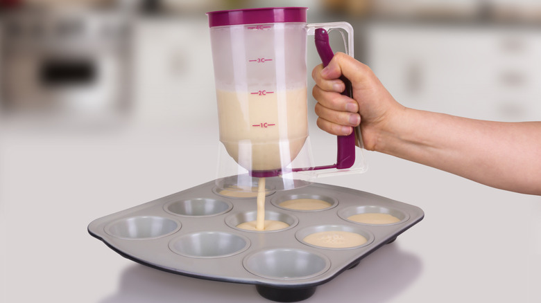 Hand using a batter dispenser for muffins