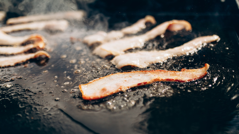 sizzling bacon pieces being cooked