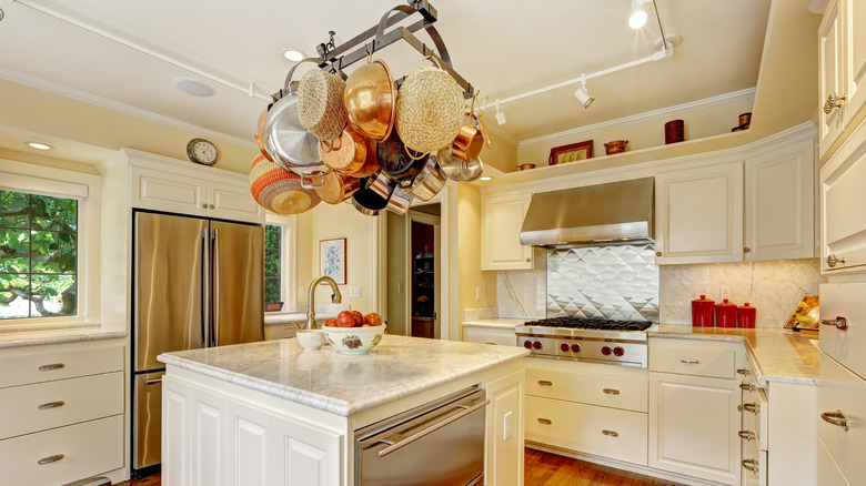 A kitchen with an overhead pot rack with pots