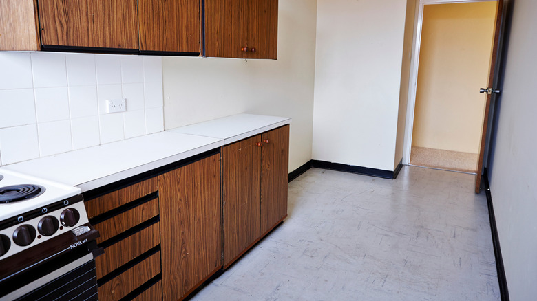 A dated kitchen with vinyl flooring