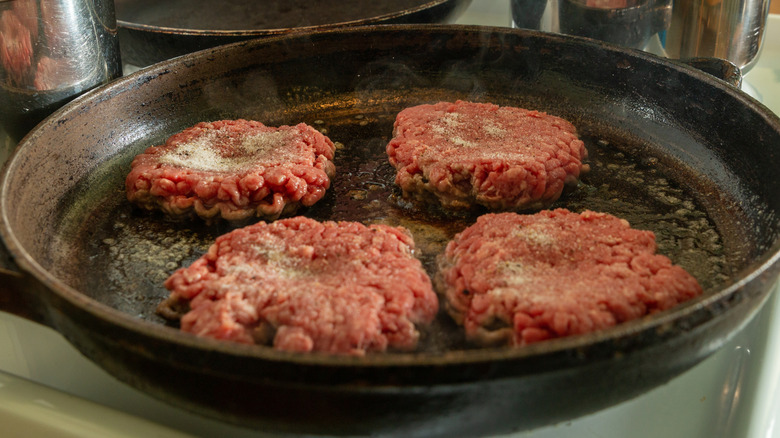 Burgers being cooked on a skillet.