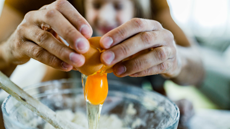 Person breaking egg over bowl